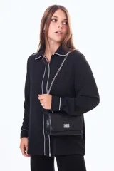 Camisa negra de manga larga con cuello estilo pijama y cierre frontal de botones. Presenta un vivo blanco en contraste que recorre el cuello, la tapeta de botones y los puños.