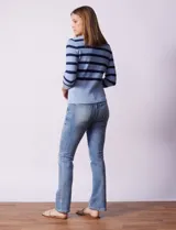 Buzo tejido de punto con diseño a rayas horizontales en tonos azul claro y azul marino. Presenta escote en V con una tapeta frontal decorada con botones metálicos y mangas tres cuartos.