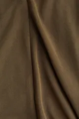 Pantalón acampanado color verde militar, de tiro alto, con costuras decorativas y nesgas en la rodilla que crean un efecto acampanado en los bajos.