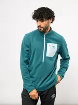 Buzo de entrenamiento Umbro con medio cierre frontal, cuello alto y bolsillo en el pecho de nylon con cierre. Presenta una textura sutil en el tejido y logo de la marca estampado en el bolsillo.