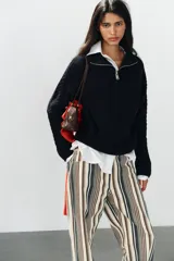 Jeans de tiro medio con diseño de rayas verticales en tonos beige, marrón y verde, corte boyfriend, cinco bolsillos y cierre frontal con cremallera y botón.