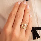 Anillo de oro 10k con diseño de nudo central y bandas laterales decoradas con pequeñas circonias engastadas.