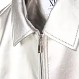 Campera de cuero sintético metalizado en color plateado, con cuello clásico, cierre frontal completo y diseño de corte recto.