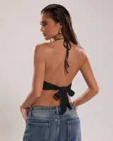 Top halter negro de tejido calado con transparencias, escote pronunciado, espalda descubierta y detalle de argolla dorada en el centro del pecho.