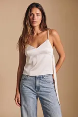 Blusa blanca de satén, corte al cuerpo con escote en V y tirantes finos. Presenta un diseño cruzado en los laterales con tiras largas para atar.