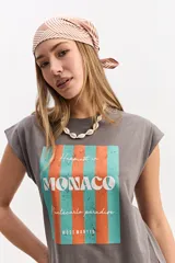 Musculosa oversize de algodón en color gris, con diseño sin mangas y estampado frontal con la palabra "MONACO" sobre franjas verticales naranjas y celestes.