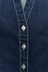Camisa de denim entallada con cuello solapa, escote en pico y manga corta. Presenta costuras marcadas y cierre frontal con botones.