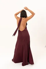 Vestido largo de color bordó, con escote halter profundo y corte a la altura de la cadera con falda amplia.