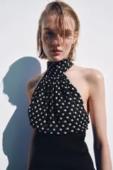 Top de cuello halter con hombros descubiertos, confeccionado con una combinación de tejidos. La parte superior presenta un estampado de lunares, mientras que la parte inferior es de tejido liso acanalado.