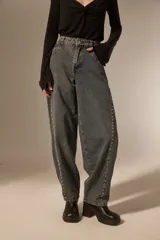 Pantalon de jean estilo barrel con lavado oscuro, tiro medio y detalle de tachas metálicas a lo largo de las costuras laterales.