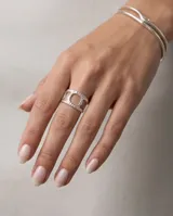 Anillo de acero quirúrgico ajustable con diseño ancho y textura punteada, que presenta una abertura geométrica central.