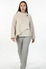 Buzo de punto color beige, con cuello alto cruzado y cierre de botón lateral. Presenta mangas largas y un diseño de corte asimétrico en el frente.