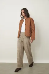 Campera acolchada color marrón claro, con cuello redondo, cierre frontal de botones y diseño de rombos.