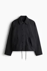 Campera de sarga levemente acolchada con cuello inglés, cierre frontal y solapa con botones. Presenta mangas raglán, bolsillos insertados delanteros, un bolsillo interior y cordón ajustable en el bajo.