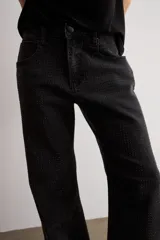 Jean estilo wide leg de tiro medio, color negro, confeccionado en denim con apliques de brillos en los laterales.