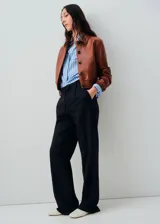 Chaqueta de cuero ovino color marrón, con diseño corto, cuello camisero, cierre frontal con botones y puños elásticos.