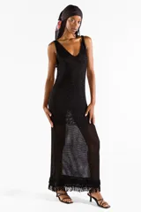 Vestido largo negro de punto abierto con sutil brillo de lúrex, escote en V y detalles de flecos en el ruedo.
