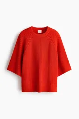 Top de punto acanalado color naranja, con cuello redondo, mangas al codo de corte raglán y diseño oversized. Presenta terminaciones acanaladas en cuello, puños y bajo.