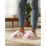 Pantuflas sin talón confeccionadas en algodón afelpado y piel sintética, con divertido estampado de manchas de vaca en tonos blanco y marrón, y suela de PVC.