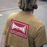 Remera color marrón claro con logo de Etnies en el cuello y estampado del logo de Independent en el pecho.
