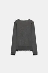 Jersey de cuello redondo y manga larga, confeccionado en tejido de punto fino. Presenta un diseño minimalista con un detalle de aplicación de encaje a tono en el bajo y en los puños.