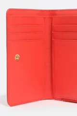 Billetera compacta Bimba y Lola de estructura rígida con textura efecto cocodrilo y acabado brillante. Cuenta con cierre de cremallera superior con tirador de tela, logo metálico dorado en el frente y compartimentos internos para tarjetas y monedas.