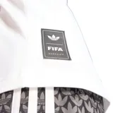 Remera Adidas de algodón con cuello redondo y corte clásico. Presenta un estampado circular en el pecho con el logo de la marca y motivos gráficos en tonos azul y rosado, inspirados en la estética del fútbol de los años 90.