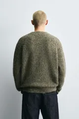 Jersey de corte relajado con textura rizada, cuello redondo y manga larga. Presenta acabados en rib en puños y ruedo.