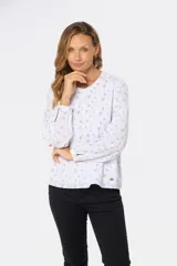 Blusa de manga larga blanca con estampado floral en negro, cuello redondo y cierre frontal con botones.