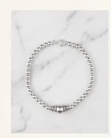 Pulsera de plata italiana 925 compuesta por esferas pequeñas, con un dije central esférico de mayor tamaño flanqueado por dos piezas decorativas con detalles labrados.
