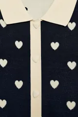 Chaqueta de punto de manga corta con estampado de corazones, cuello polo y cierre frontal con botones en forma de corazón.