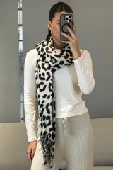 Bufanda rectangular con estampado animal print en tonos blanco y negro, con terminaciones de flecos en los extremos.