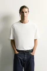 Camiseta relaxed fit color blanco, de cuello redondo y manga corta. Presenta un pequeño parche aplicado a contraste en el extremo de la manga y terminaciones en rib.