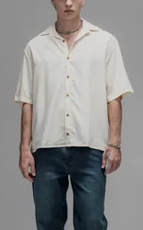 Camisa de manga corta con cuello cubano y cierre frontal de botones, de corte oversize y diseño minimalista.