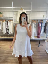 Vestido corto blanco, sin mangas, de corte suelto y con un volante en el ruedo.