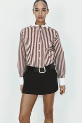 Falda pantalón de tiro medio color negro, con bolsillos delanteros y detalle de cinturón integrado con hebilla metálica dorada. Cierre frontal con cremallera y gancho.
