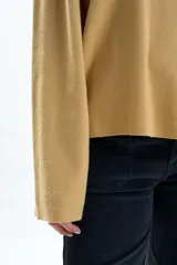 Buzo de tejido de punto color mostaza, de corte holgado, con cuello redondo acanalado y mangas anchas tipo campana.