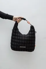 Cartera tipo hobo de Rotunda, color negro, con diseño acolchado en cuadrados y detalle de eslabón plástico en la manija. Incluye parche con el logo de la marca en el frente.