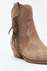 Bota texana de gamuza negra con caña baja, flecos laterales decorativos, costuras estilo western y taco bajo inclinado.