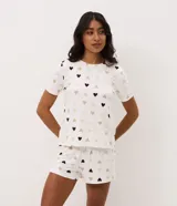 Short de pijama Lov de color blanco con estampado integral de corazones en tonos marrones, verdes y rosados. Cuenta con cintura fija, bragueta con un botón y corte regular.