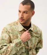 Campera trucker de Marfinno para hombre, con diseño de estampado floral en tejido jacquard texturizado de tonos verdes y beige. Presenta cuello camisero, cierre frontal de botones metálicos y bolsillos en el pecho.