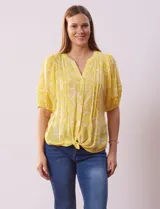 Blusa amarilla estampada con cuello en V, manga corta con volados y ruedo anudado.