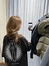 Remera oversize de color marrón topo con efecto acid wash, cuello redondo y manga corta. Cuenta con un pequeño estampado gráfico frontal con el texto 'WAKE UP IND' y una calavera.