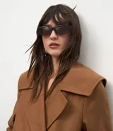 Campera pesada de estructura firme, color marrón, con cuello amplio de solapa alargada, cierre cruzado con botones, mangas largas y bolsillos delanteros. Presenta un canesú sobrepuesto en la espalda con pliegue central.