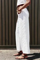 Pantalón blanco de jean con bordados calados en los laterales, de tiro medio y pierna ancha.