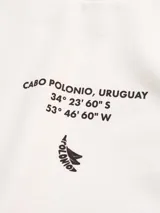 Remera oversize de algodón blanca con estampado frontal de coordenadas y texto "Cabo Polonio, Uruguay" en color marrón.