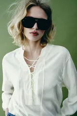 Camisa blanca ZARA Woman Collection de 100% seda, con escote en V ajustable con cordones entrelazados y manga larga con puños rectos.