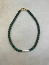 Collar artesanal compuesto por cuentas de piedra volcánica en diversos tonos y tamaños, con una perla natural de río como dije central y cierre metálico dorado.
