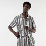Camisa de manga corta con cuello solapa y cierre frontal de botones, con diseño de rayas verticales en tonos negro y blanco.