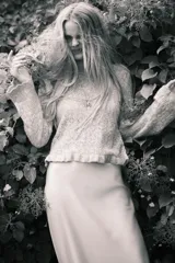 Buzo corto de punto pointelle color gris, con cuello redondo, mangas largas y terminaciones festoneadas en cuello y puños. Presenta un ribete acanalado con volados en el bajo.